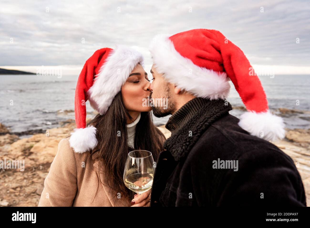 Baiser passionné de couple amoureux sur les rochers de mer en hiver vacances de noël en mer et du nouvel an - Jeune belle petite amie et le port de collage boyfriend Banque D'Images