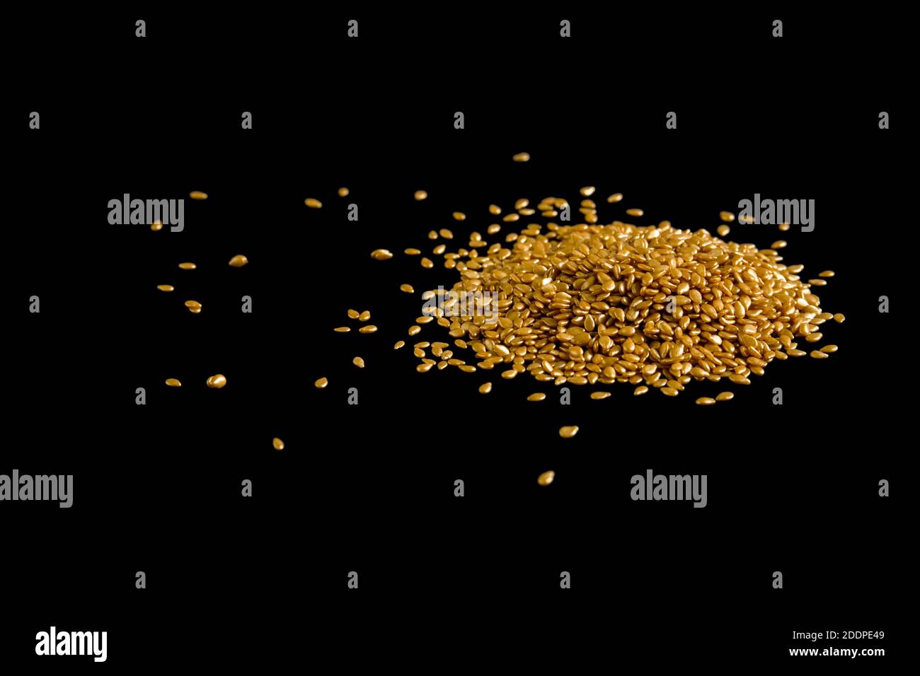 Pile de graines de sésame plaquées or sur fond noir Banque D'Images