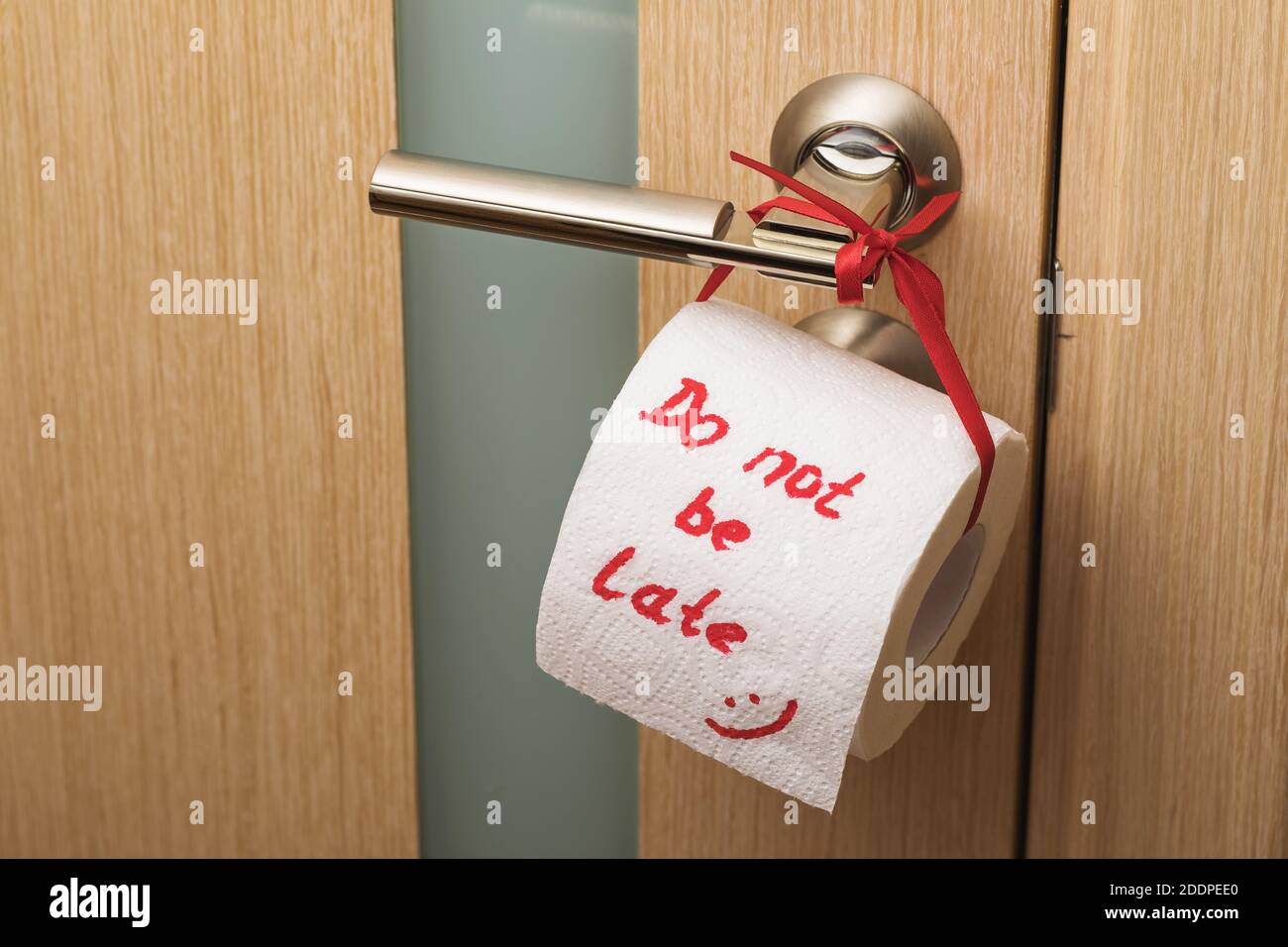 Rouleau de papier hygiénique attaché à la poignée de porte, grand plan. Plaisantez sur le manque d'hygiène dans les toilettes Banque D'Images