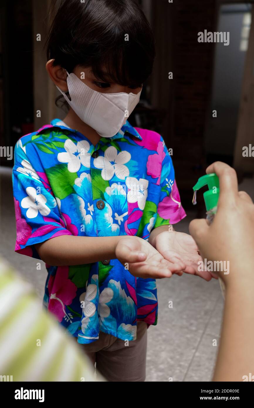 Garçon d'Asie du Sud-est utilisant du gel désinfectant liquide pour les mains. Protection contre les virus infectieux hygiène et mode de vie sain. Banque D'Images