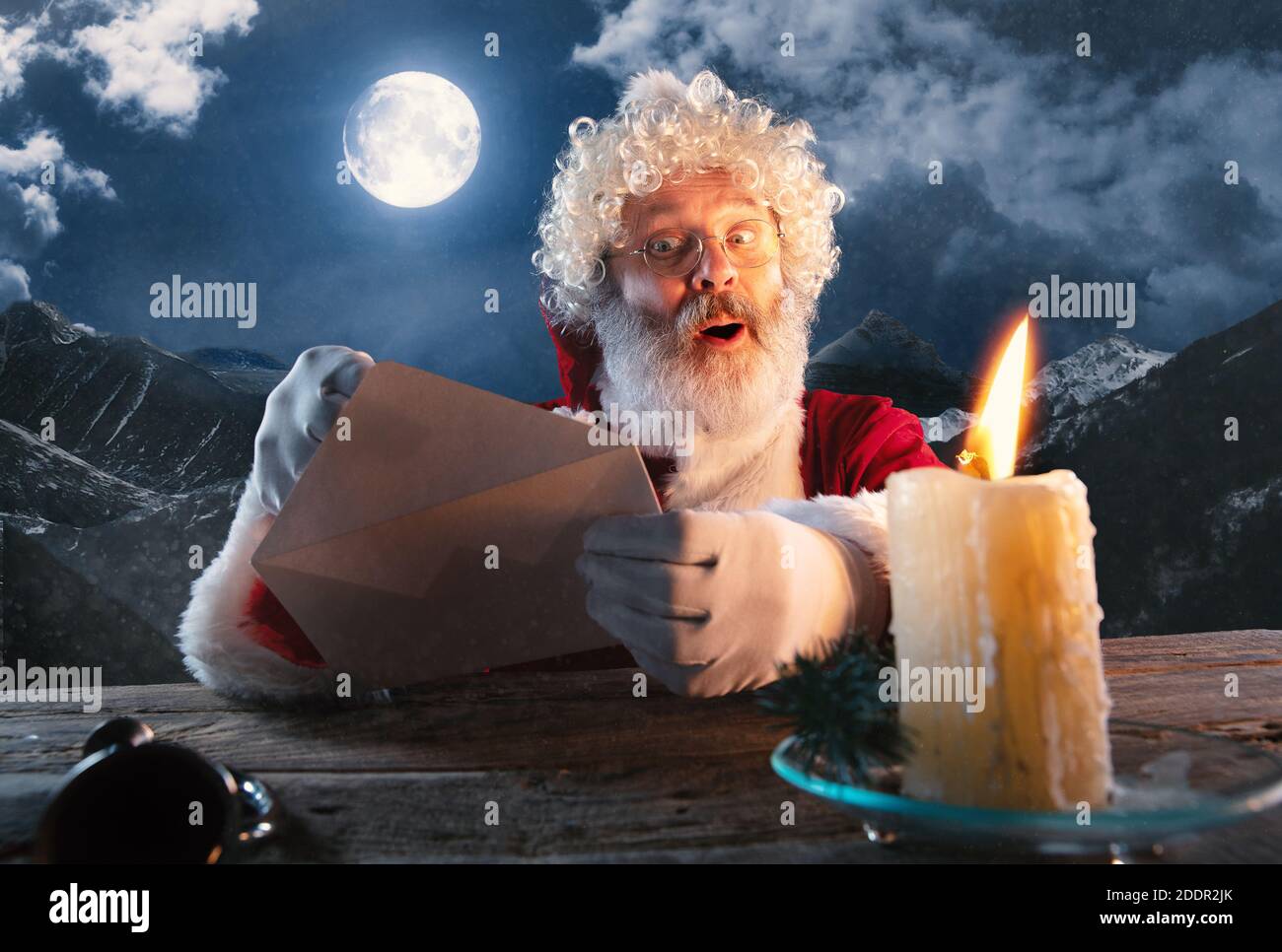 Cordialement. Le Père Noël émotionnel félicite le nouvel an 2021 et Noël. Homme en costume traditionnel envoyer une lettre, liste de souhaits illuminée avec bougie et forêt de nuit sur fond. Hiver, vacances Banque D'Images