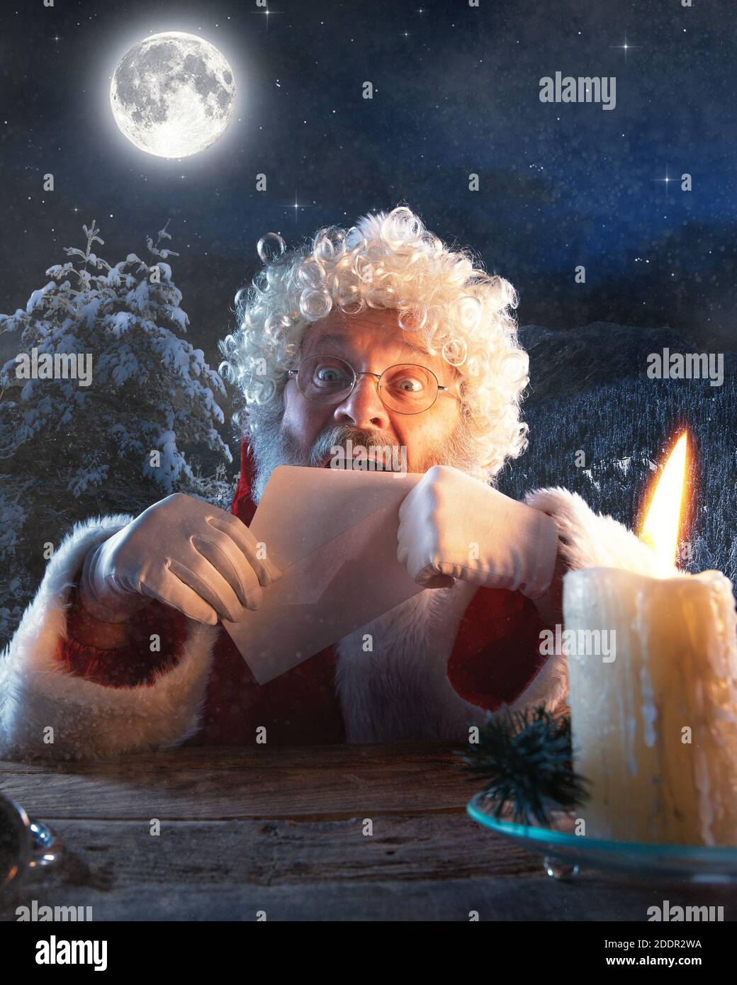 Cordialement. Le Père Noël émotionnel félicite le nouvel an 2021 et Noël. Homme en costume traditionnel envoyer une lettre, liste de souhaits illuminée avec bougie et forêt de nuit sur fond. Hiver, vacances Banque D'Images