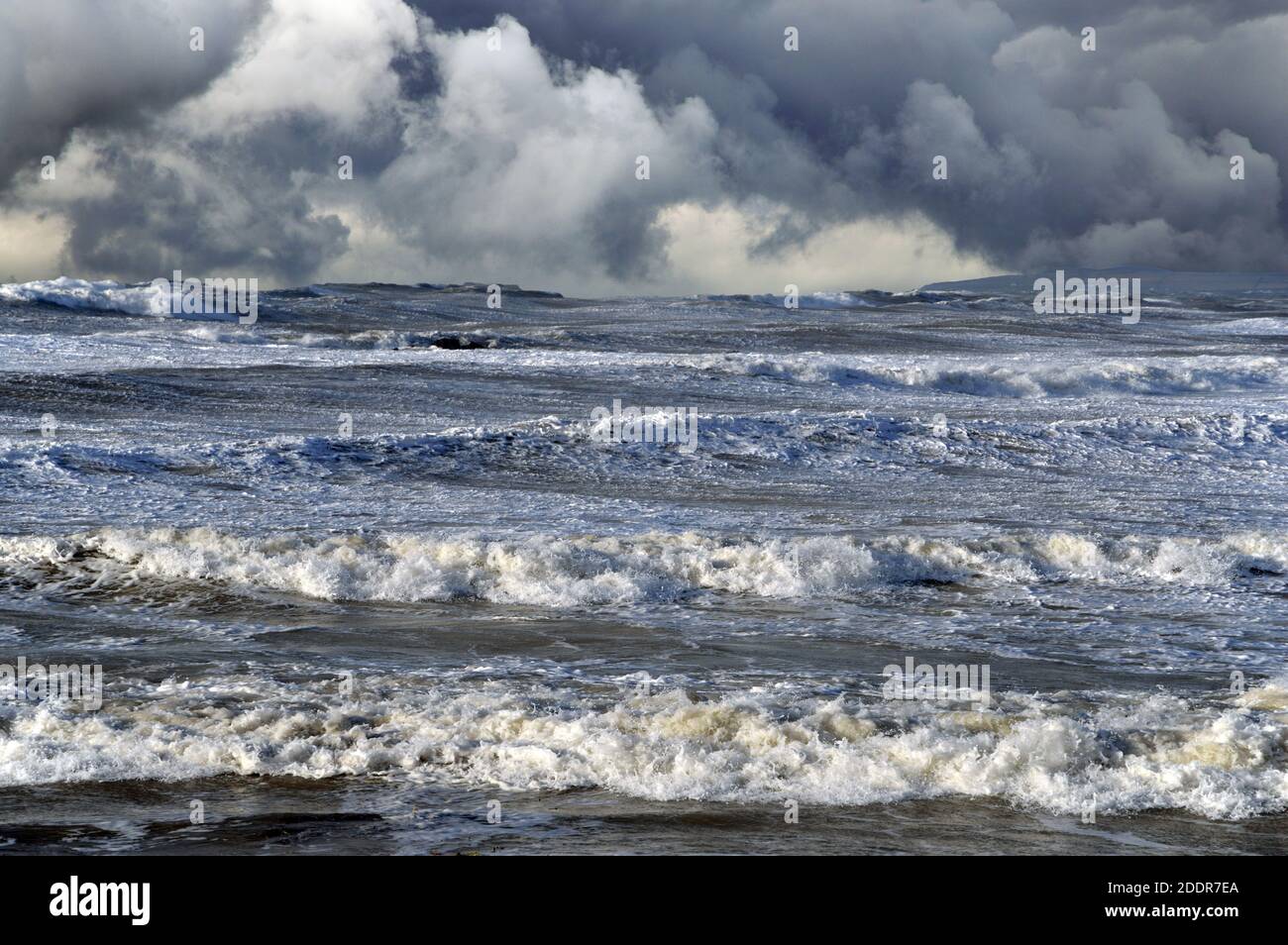 On voit ici des mers sauvages dans des vents de force gale au large de la côte d'Anglesey. Le ciel spectaculaire a été ajouté à l'aide de Photoshop. Banque D'Images