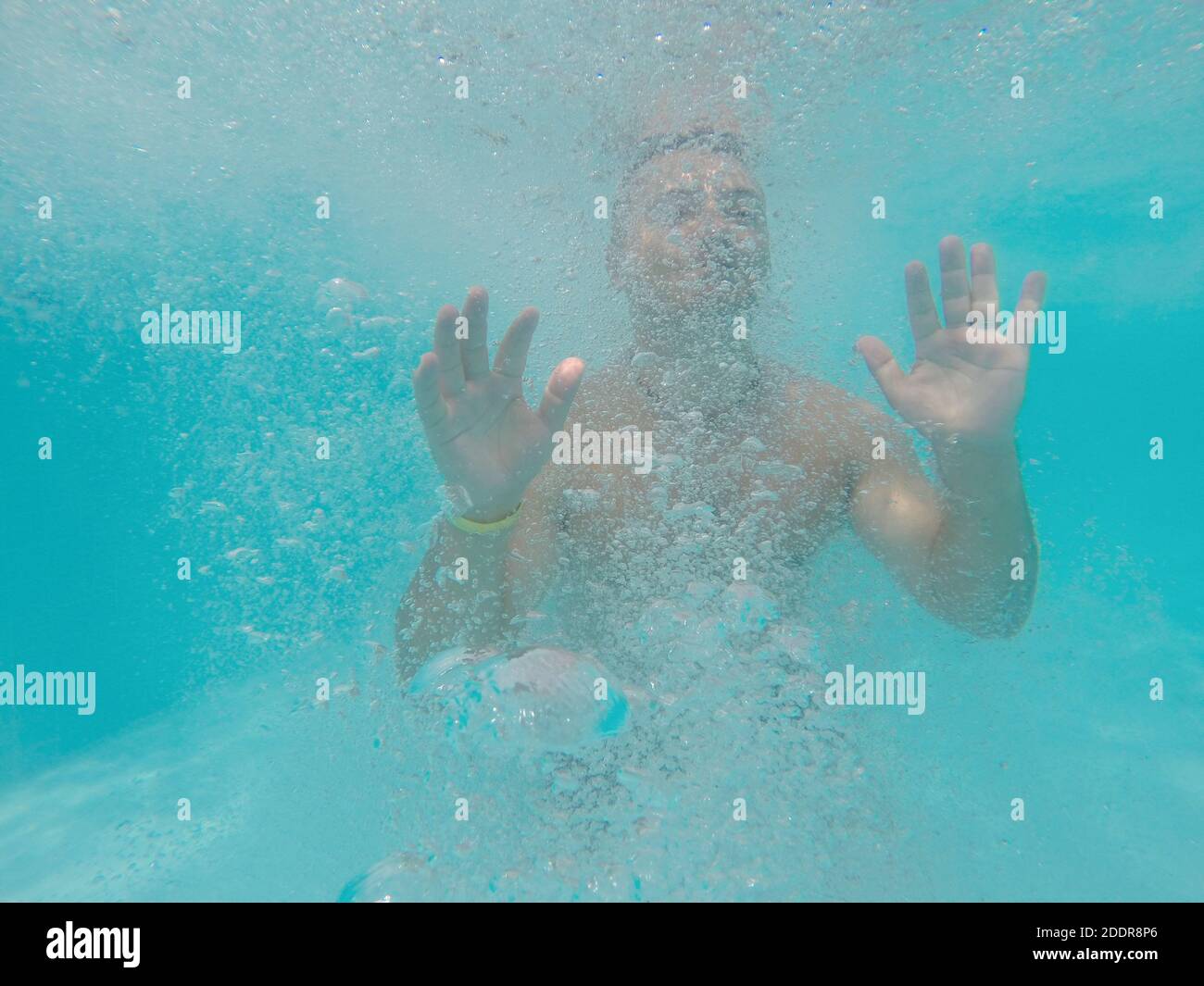 Jeune homme noyant sous l'eau dans la mer ou l'océan, eau bleue avec des bulles Banque D'Images