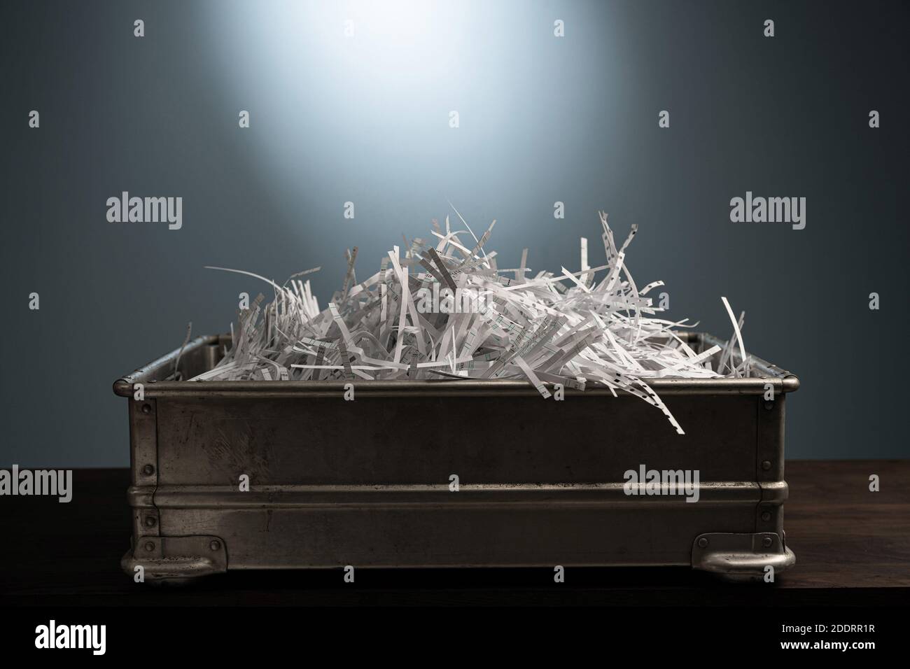 Des feuilles de papier blanches se trouvent dans des bandes coupées dans une boîte métallique pour les déchets de bureau. Banque D'Images