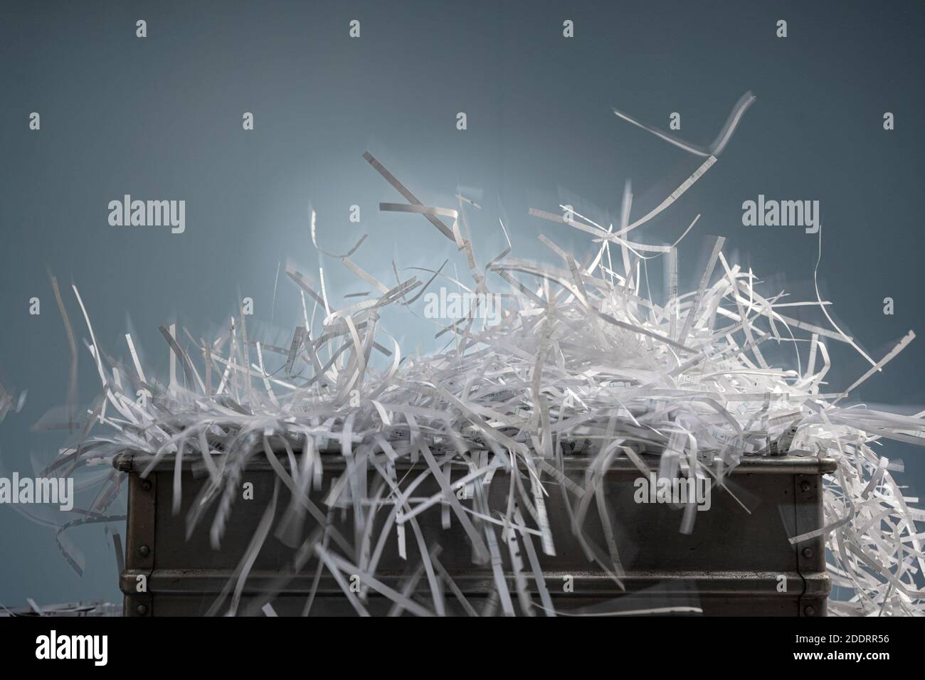 Les rayures de papier déchiquetées semblent exploser dans une boîte et étendre le volume qui s'étend sur le bord de la boîte Banque D'Images
