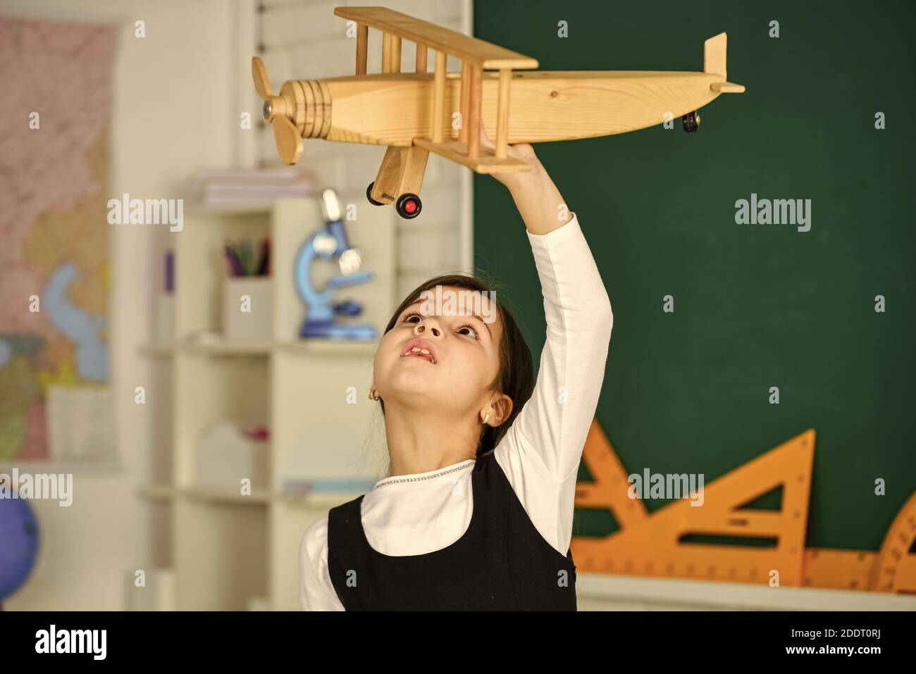 Rêvez toujours. Écolière jouer en bois jouet avion. Voler en avion. Etude de la géographie. Dans le monde entier. Rêves de voyage. Retour à l'école. Histoire sur les vacances d'été. Comment j'ai passé l'été. Voyage en avion. Banque D'Images