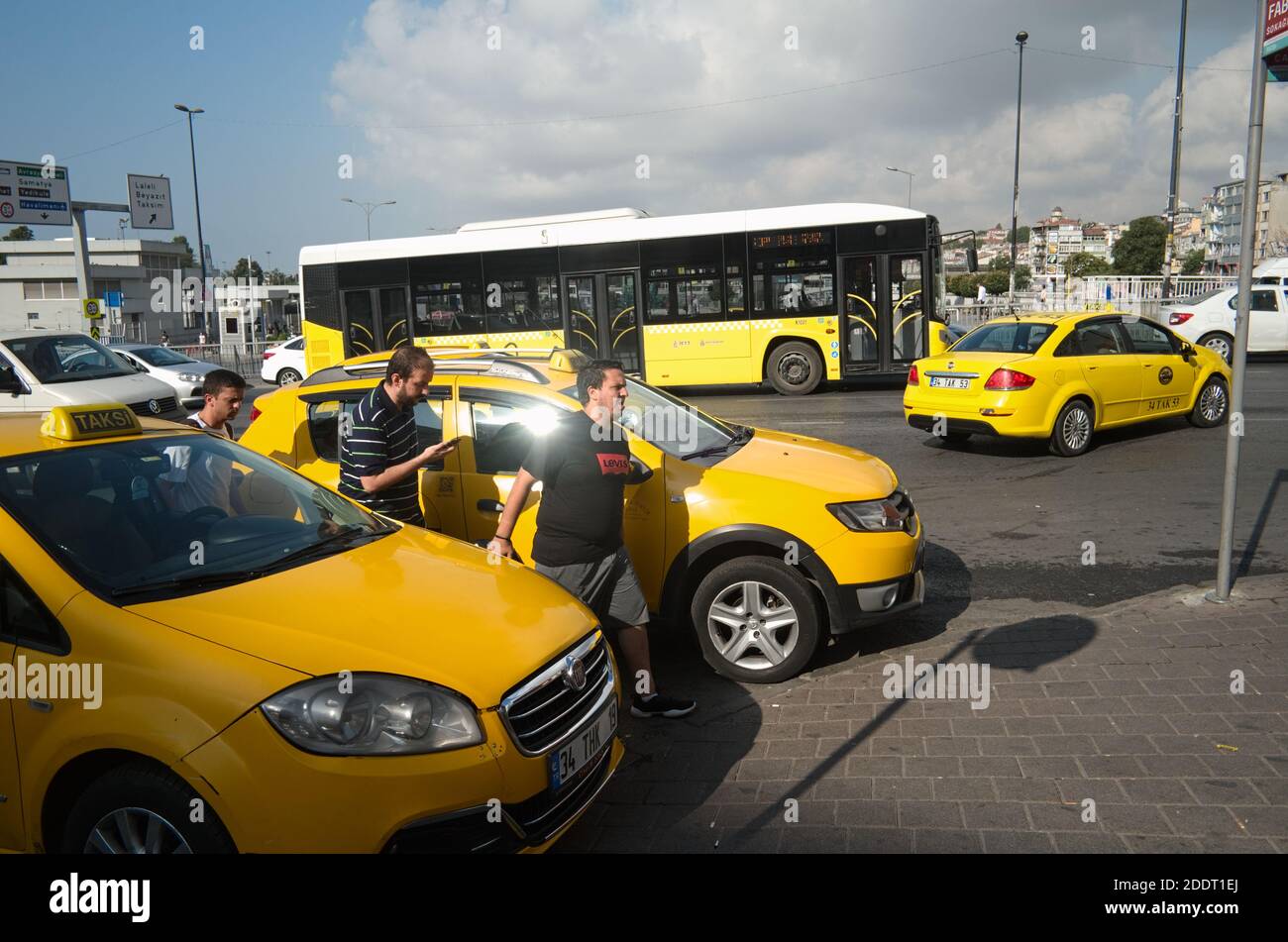 Istanbul, Turquie - septembre 2018 : trois jeunes hommes franchissent la route près des taxis jaunes dans la rue d'Istanbul. Image couleur jaune vif pour la plupart. Banque D'Images