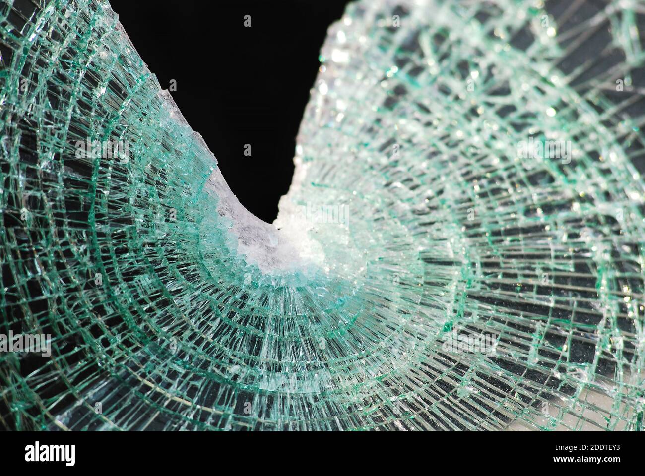 Le verre feuilleté brisé d'un pare-brise affiche une toile d'araignée classique fissurée après l'impact avec un espace triangulaire sur le dessus. Arrière-plan noir. Banque D'Images