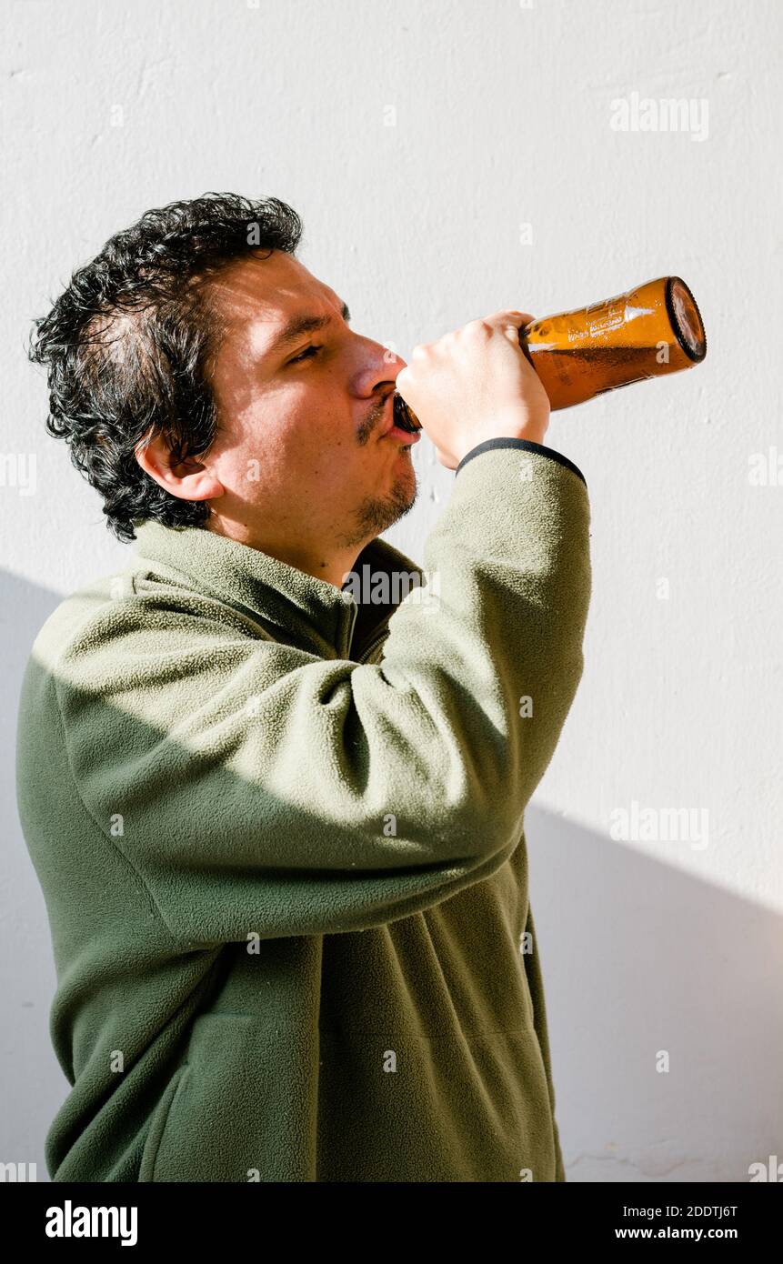 Homme ivre avec un problème d'alcool debout prenant de la bière d'une bouteille Banque D'Images