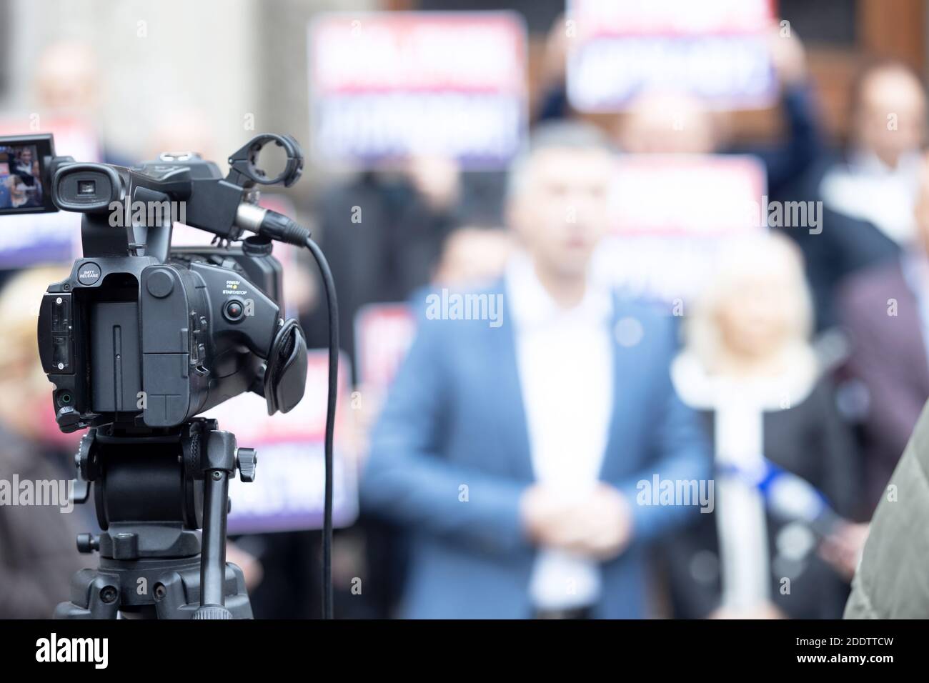 Concentrez-vous sur la caméra vidéo filmant la conférence de presse, groupe flou de personnes tenant des affiches de protestation en arrière-plan Banque D'Images