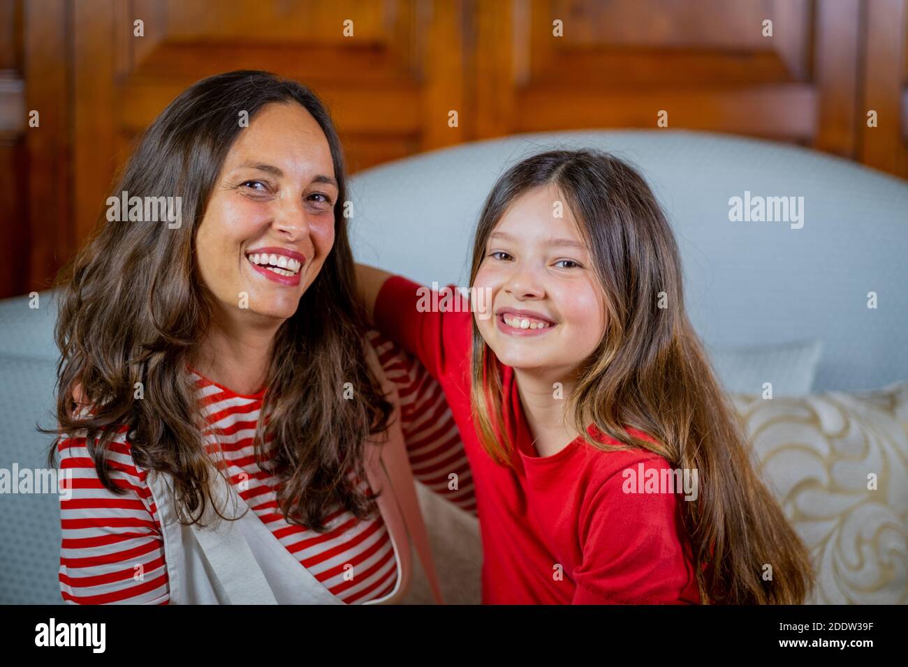 Portrait de la mère et de la fille rient et s'assoyent ensemble Sur le canapé - Portrait numérique de la famille Banque D'Images
