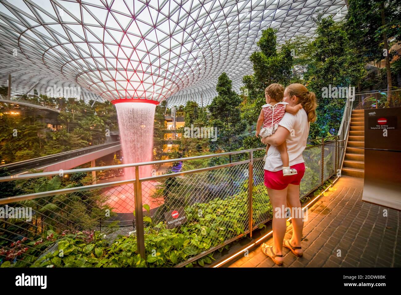 singapour, singapour - 4 mars 2020 : la jeune mère tient une petite fille les voyageurs regarde la chute d'eau dans le centre commercial Jewel à singapour changi international Banque D'Images