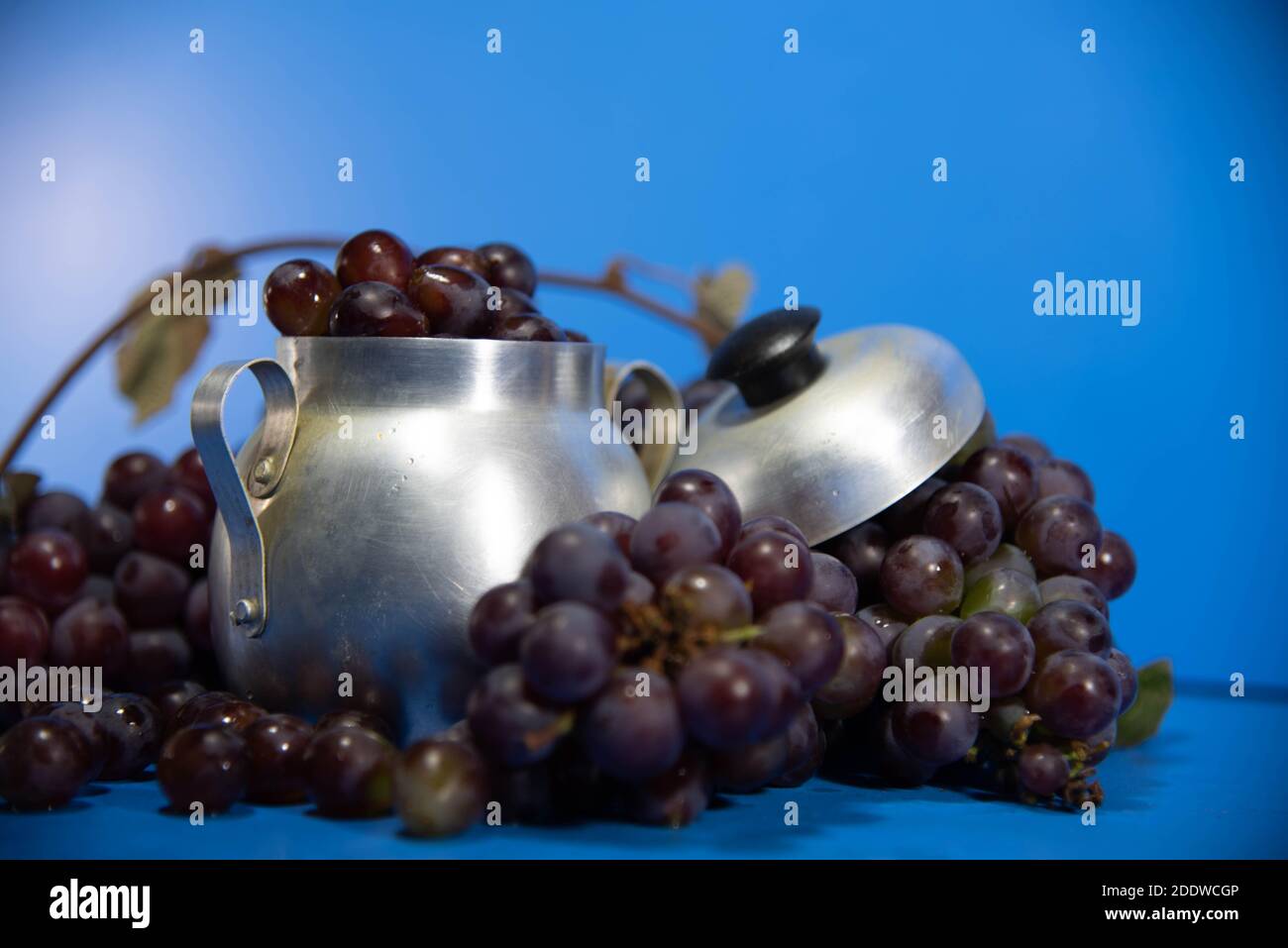 Fruits et baies de raisin frais. Fond bleu . Ingrédient pour les jus et le vin. Baies de raisin en aluminium. Banque D'Images