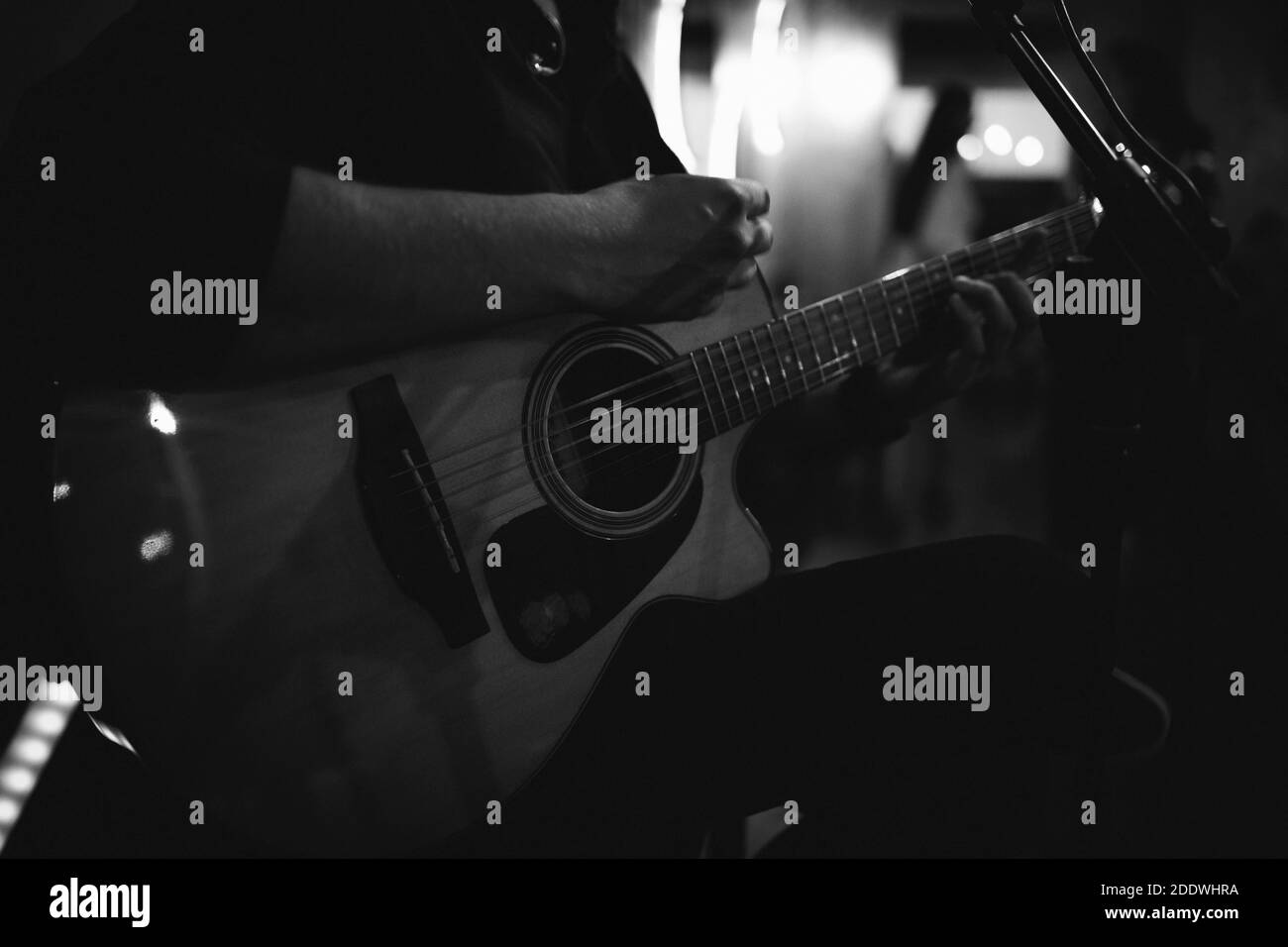 Un cliché en niveaux de gris d'un homme assis jouant de la guitare et chant Banque D'Images