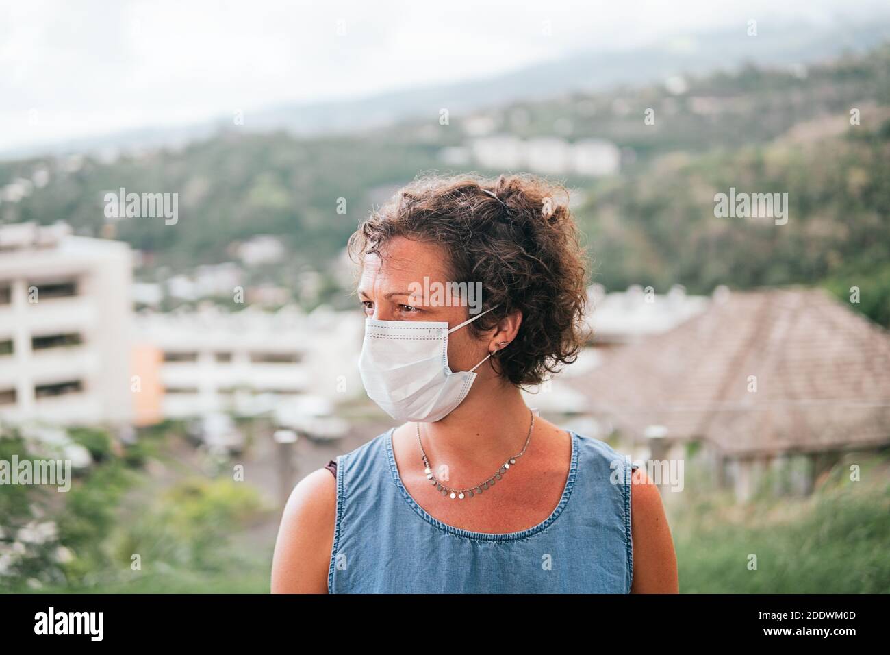 Photo de stock de femme adulte portant un masque jetable en raison de covid19 regardant sur le côté. Banque D'Images