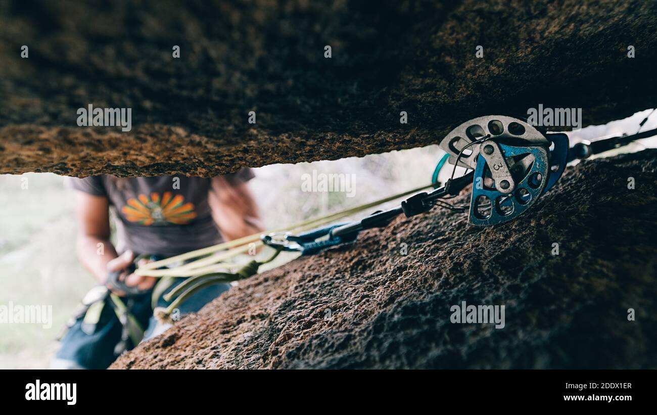 Détail de l'équipement de varappe entre deux rochers. Il y a une personne non reconnue en arrière-plan. Banque D'Images