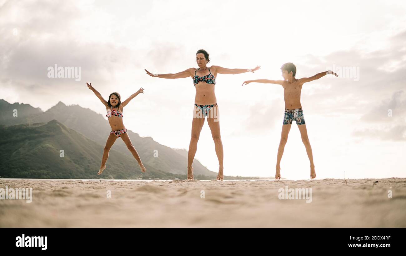 Photo de la femme et de ses enfants qui sautent sur la plage. Banque D'Images