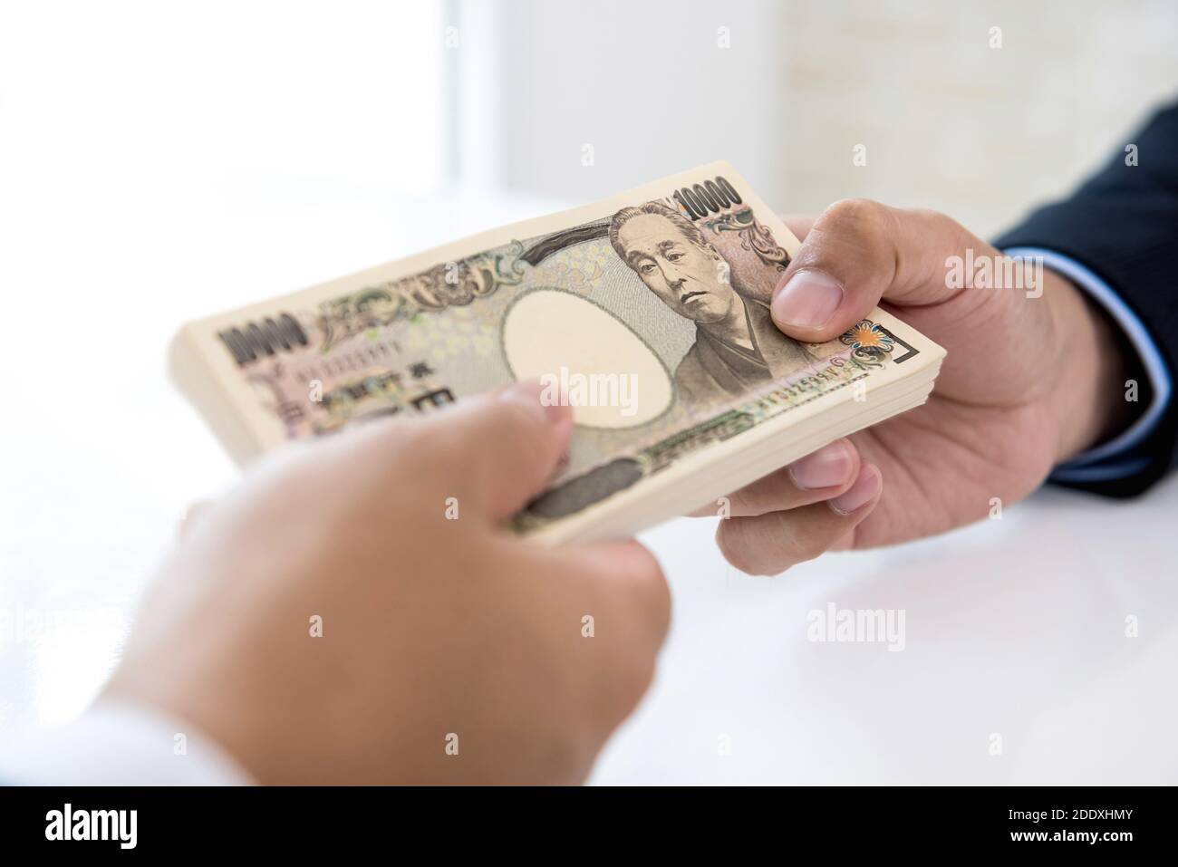 Homme d'affaires donnant de l'argent sous forme de monnaie japonaise yen à son partenaire pour le service rendu - financier, prêt et paiement en espèces concepts Banque D'Images