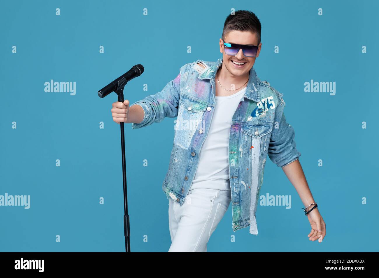 beau chanteur heureux en denim et lunettes de soleil avec microphone sur  fond bleu. espace pour le texte Photo Stock - Alamy