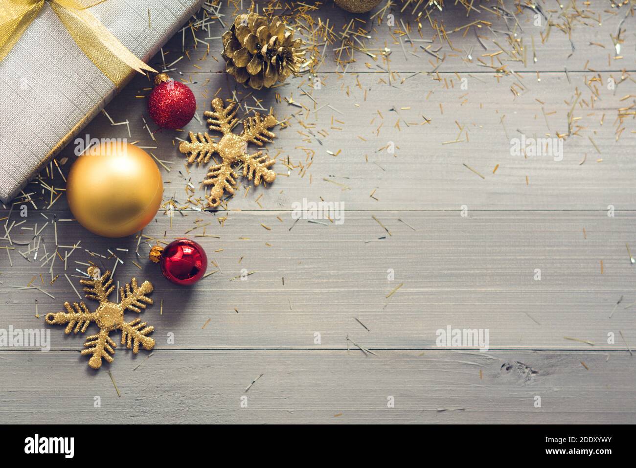 Boîte-cadeau argentée avec décorations de Noël pailletées rouge et or éléments sur fond en bois, vue de dessus avec espace de copie Banque D'Images