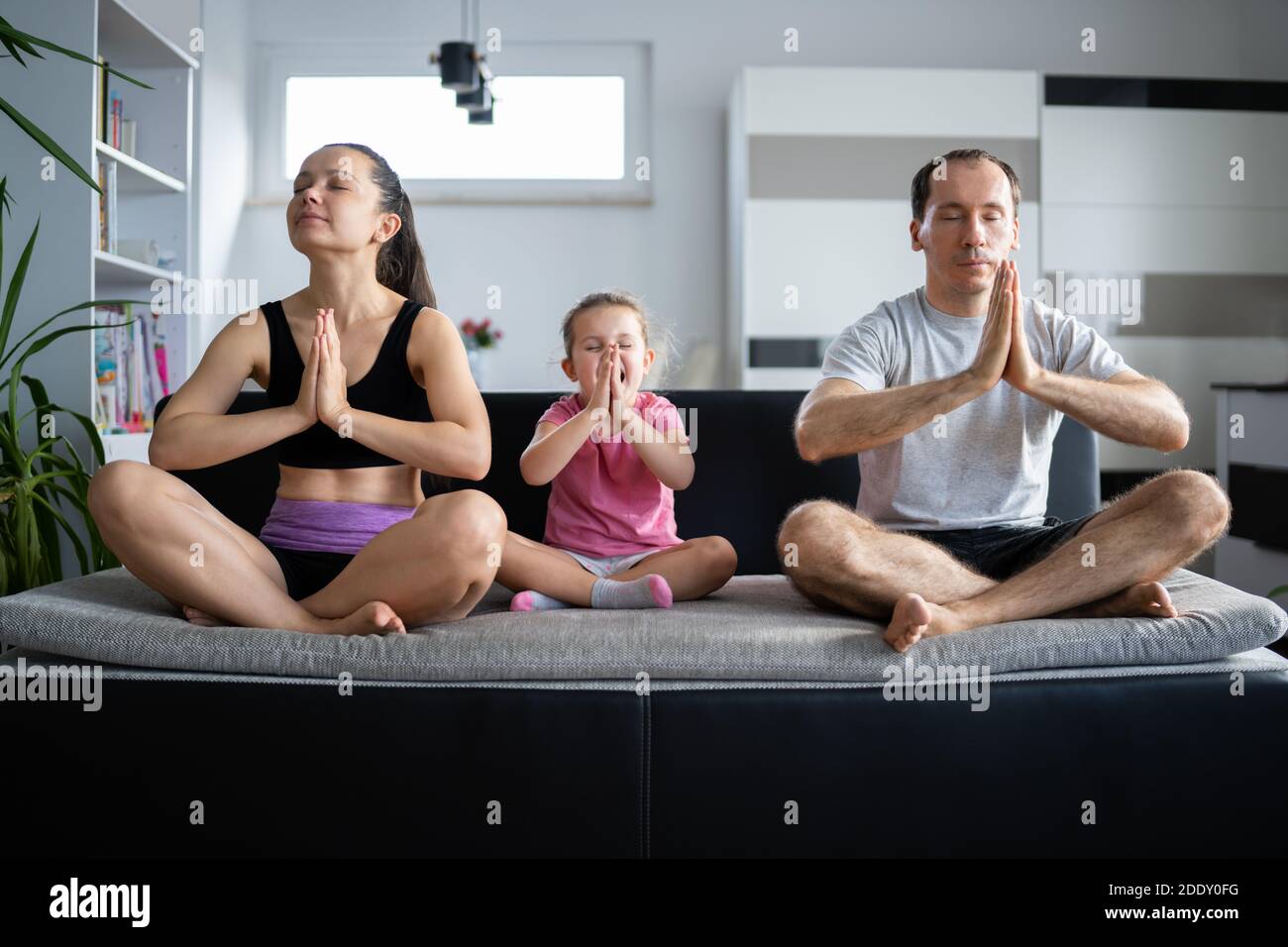 Famille adulte avec méditation de yoga de fille à la maison Banque D'Images