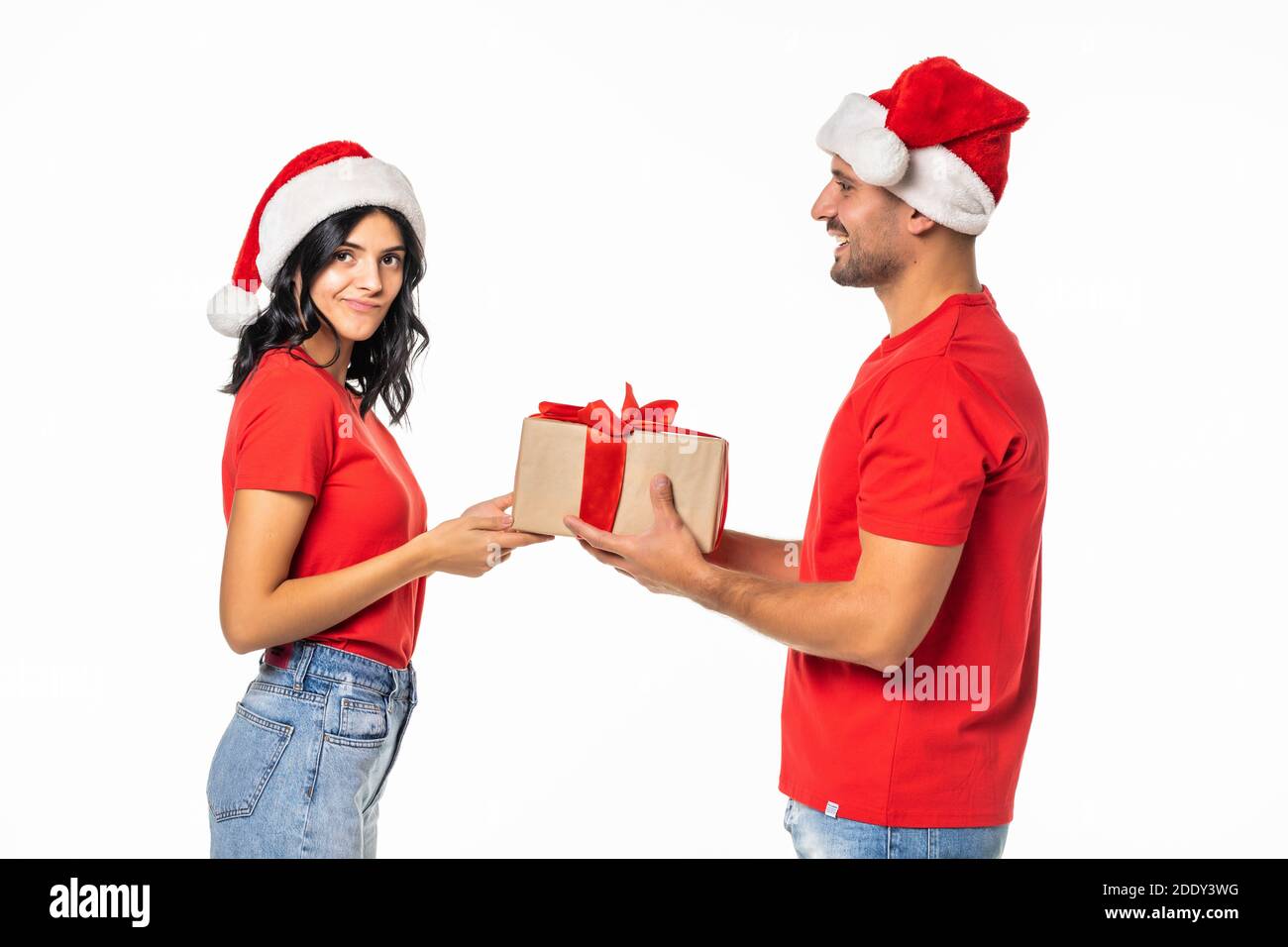 Couple heureux excité avec cadeau souriant regardant l'un l'autre, porter chapeau rouge nouvel an, isolé sur fond blanc Banque D'Images