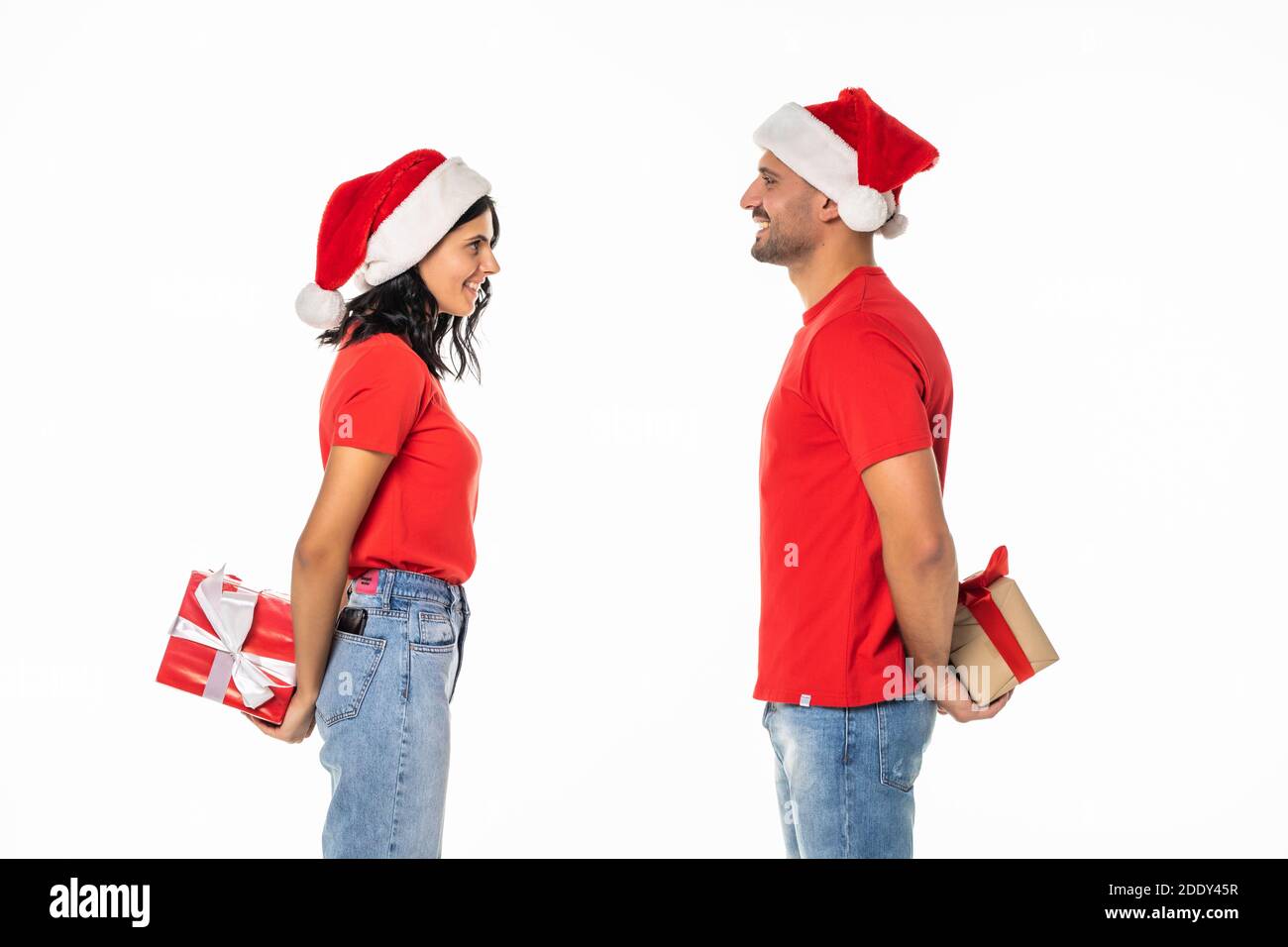 Vue latérale jeune Santa couple amis homme femme à Noël chapeau boîte à cadeau avec ruban noeud isolé sur fond blanc. Joyeux nouvel an cel Banque D'Images