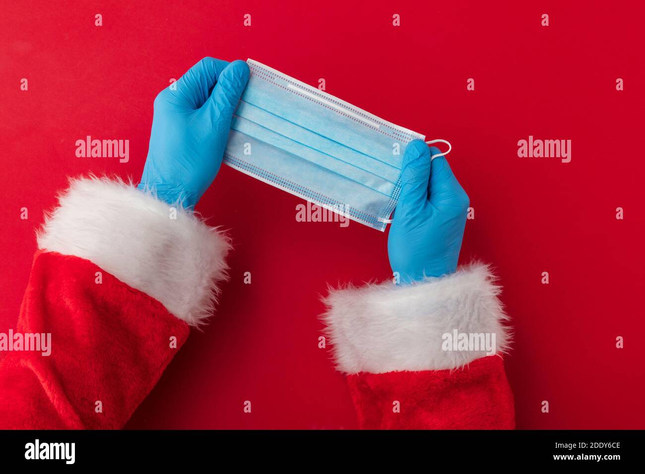 Mains du Père Noël portant un masque chirurgical de coronavirus. Noël Covid Banque D'Images