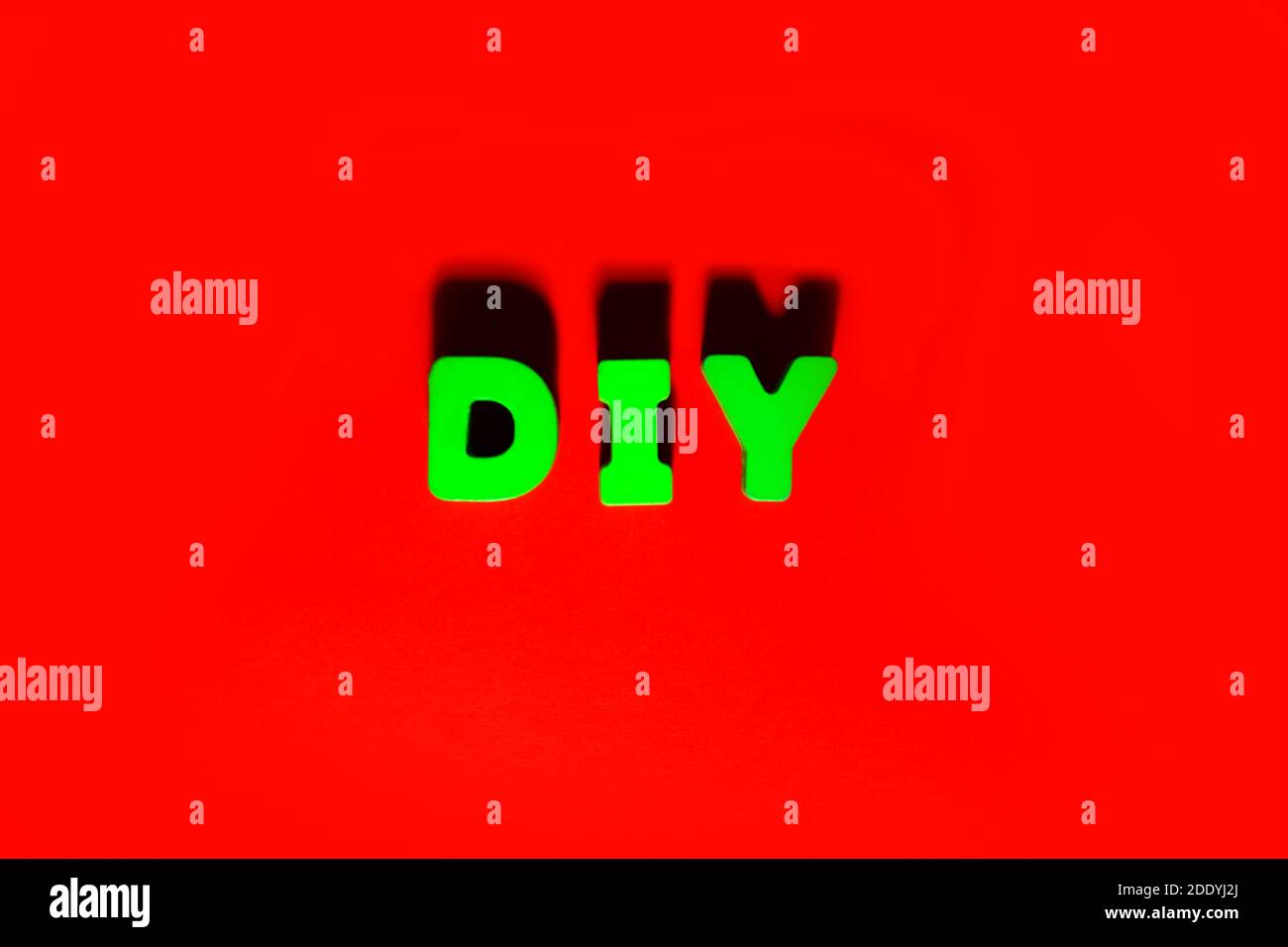 Mot DIY - faites-le vous-même l'orthographe par des lettres sculptées en bois vert sur fond rouge avec ombres et volume, fait à la main, artisanat, hobbie, maison de loisirs con Banque D'Images