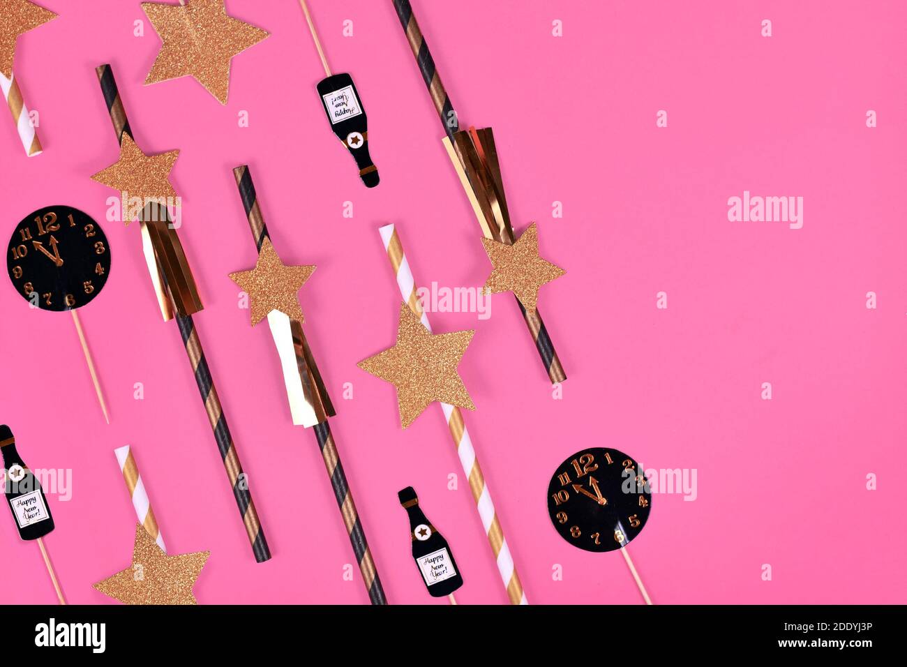 Nouvel an Silvester célébration plat avec étoiles en papier à rayures dorées, noires et blanches et flûte champaign et décoration en papier horloge sur fond rose Banque D'Images