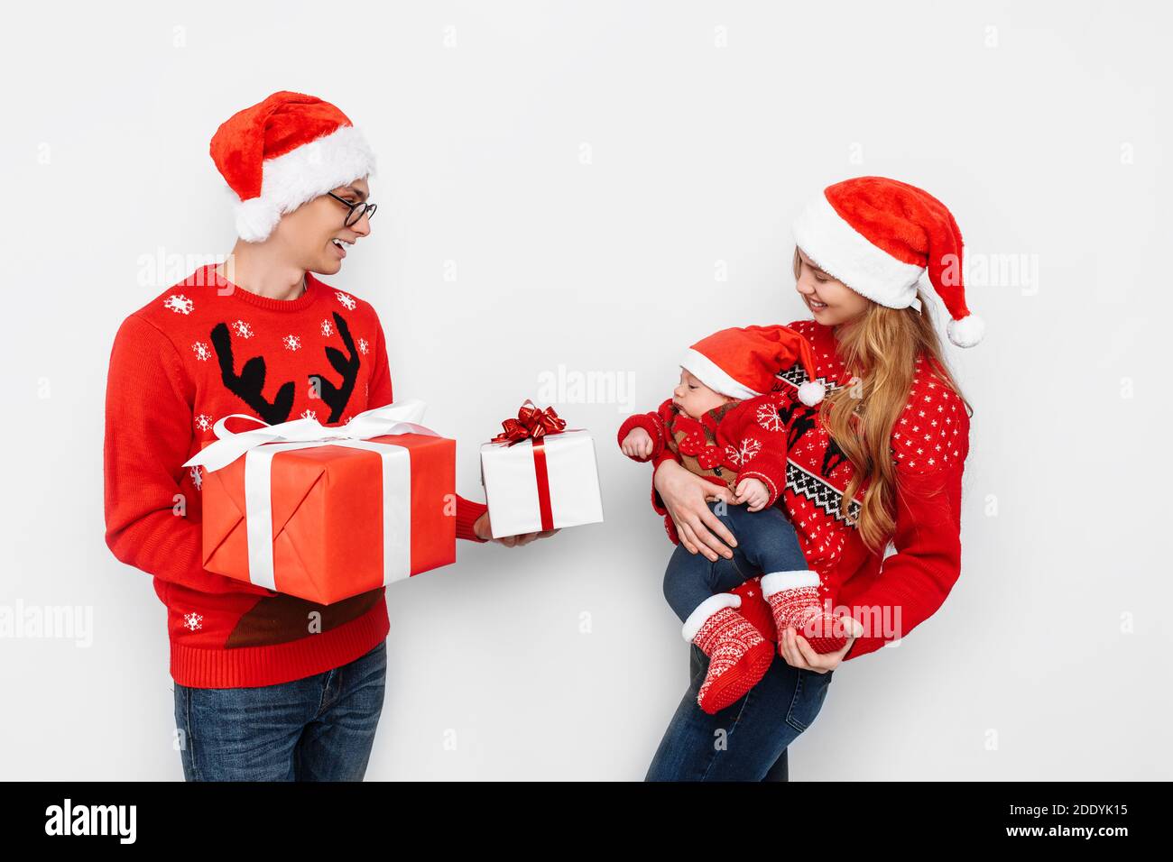 Joyeux famille dans les chapeaux de père Noël, papa maman et petit bébé,  papa donne à son fils un cadeau de Noël, sur un fond blanc Photo Stock -  Alamy