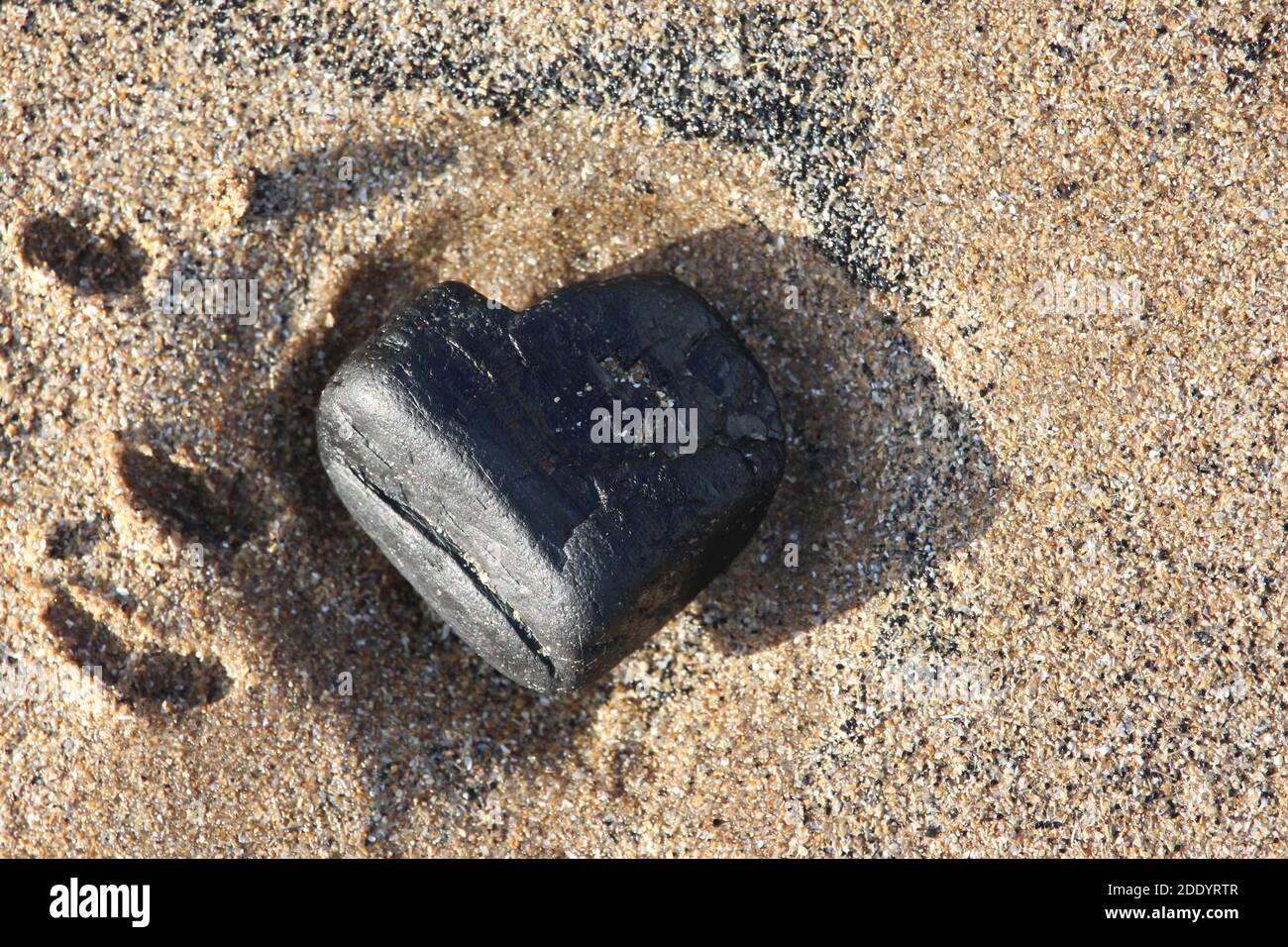 Une photographie rapprochée d'une masse de charbon ou rock sur une plage de sable en forme de cœur Banque D'Images