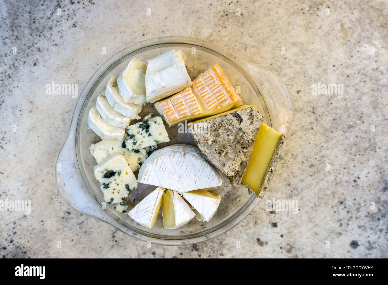 Assortiment de différents types de délicieux fromages dans une assiette en verre sur une table en pierre. Vue de dessus. Banque D'Images