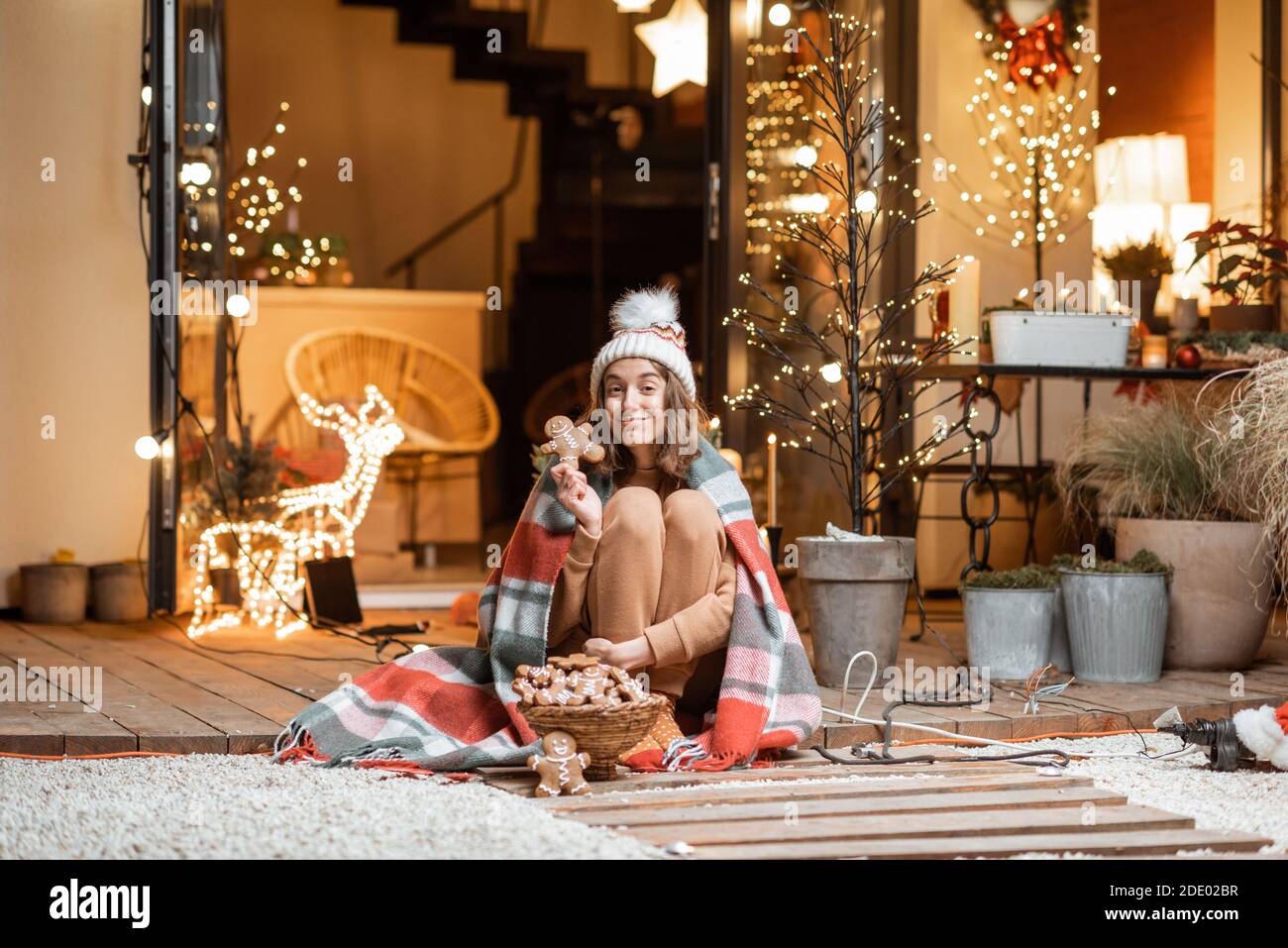 Jeune femme célébrant seul le nouvel an assis avec des pains d'épice doux sur une terrasse à la maison. Concept de quarantaine et d'auto-isolement pendant l'épidémie en vacances Banque D'Images