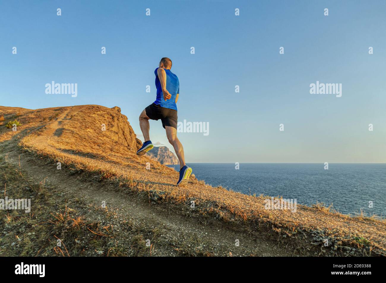 dos homme coureur athlète courir en amont dans le ciel bleu de fond et la mer Banque D'Images
