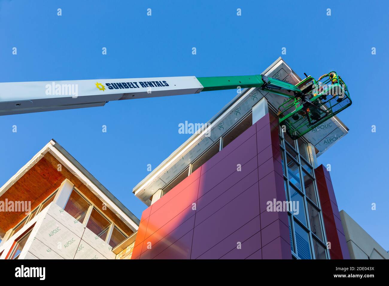 Les travailleurs d'un ascenseur de picker de cerisier atteignent le sommet d'un bâtiment afin de laver les fenêtres extérieures dans le centre-ville de fort Wayne, Indiana, États-Unis. Banque D'Images