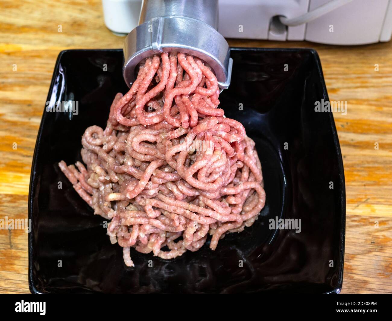 vue avant du broyage de viande hachée et d'oignon moulin à viande électrique sur une table en bois dans la cuisine maison Banque D'Images