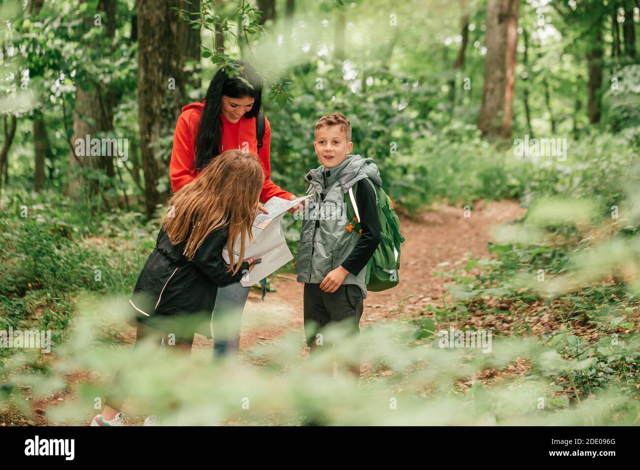 Belle mère avec deux enfants se promo dans la forêt, en utilisant une carte et en planifiant une randonnée. Bonne famille s'amuser ensemble.Selective Foc Banque D'Images