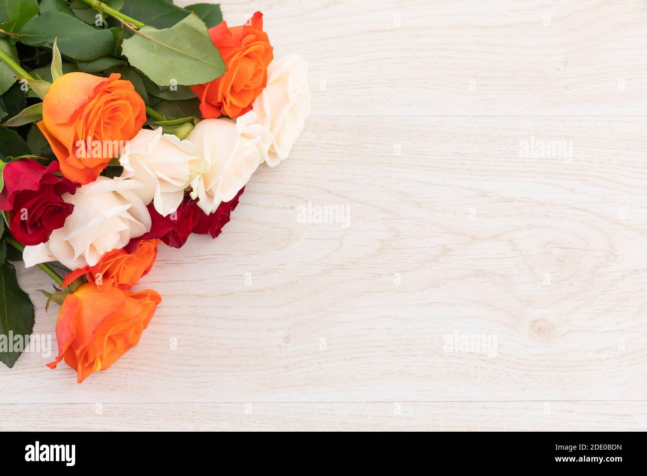 Bouquet de roses orange, blanc et rouge sur fond de bois Banque D'Images