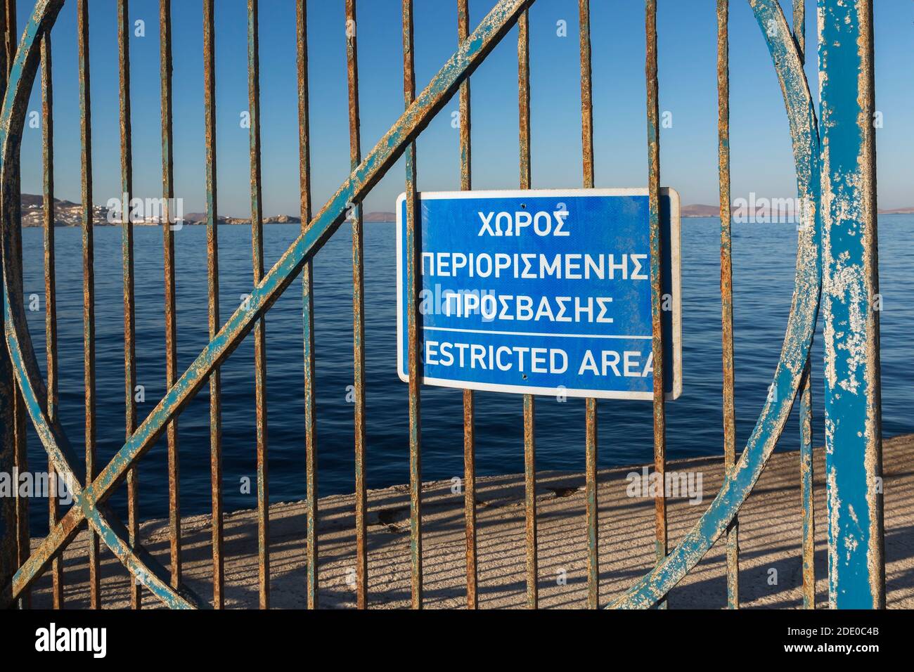 Gros plan du panneau d'avertissement de zone réglementée en grec et en anglais affiché sur la porte en fer rouillé bleu, nouveau port de Mykonos, île de Mykonos, Grèce Banque D'Images