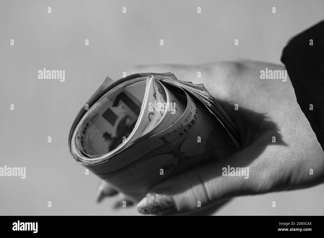 Main tenant de l'argent roulé, tenant des billets en euros sur un fond flou, monnaie EN EUROS . Banque D'Images