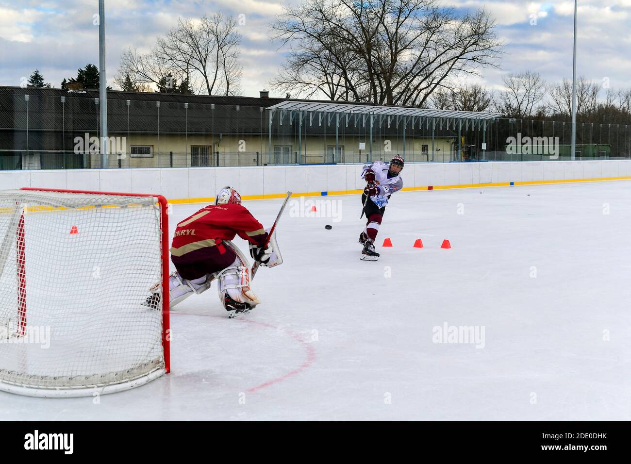 un joueur de hockey de jeunesse prend des coups de feu sur le gardien de but pendant le hockey sur glace en plein air formation Banque D'Images