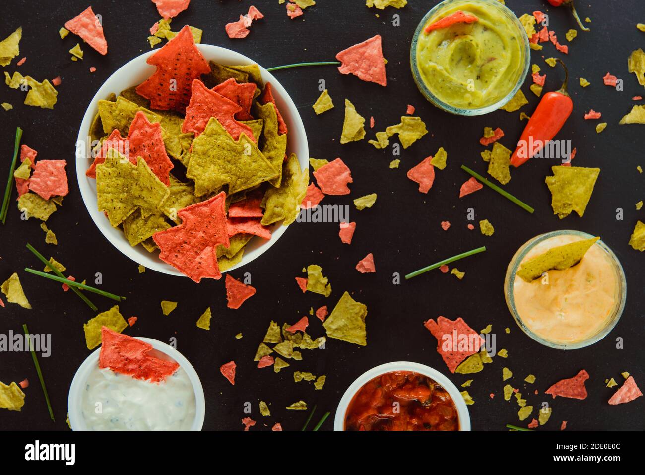 Vue du haut maïs vert et rouge tortilla chips en forme d'arbre de Noël dans un bol blanc avec salsa, guacamole, fromage, crème aigre trempant sauces Banque D'Images