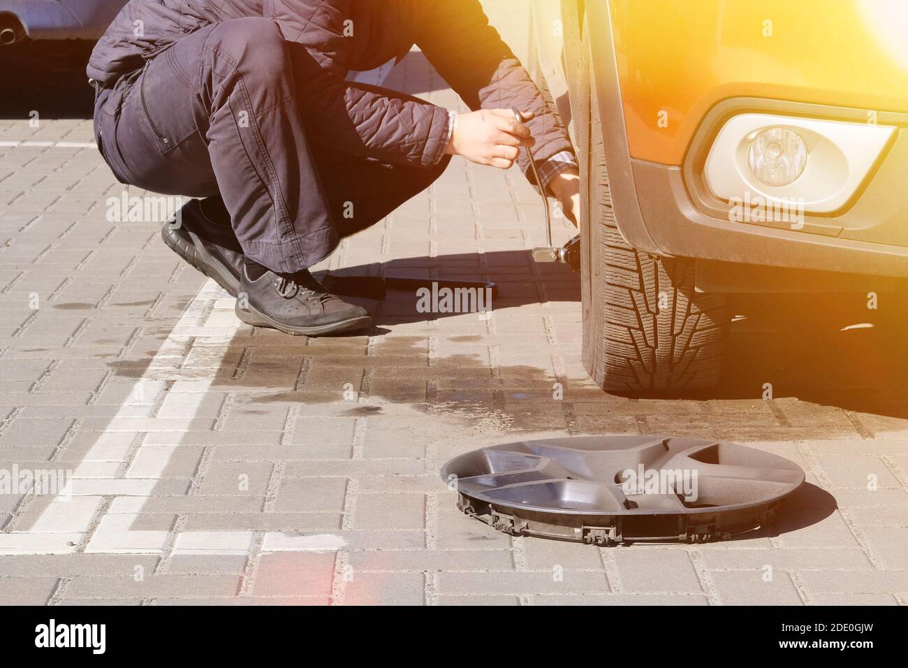L'homme prend le cric de voiture pour changer de pneu. Pneus de voiture et roues avec roues. Service de voiture. Changer un pneu de voiture crevé sur route. Homme change de pneus. Banque D'Images
