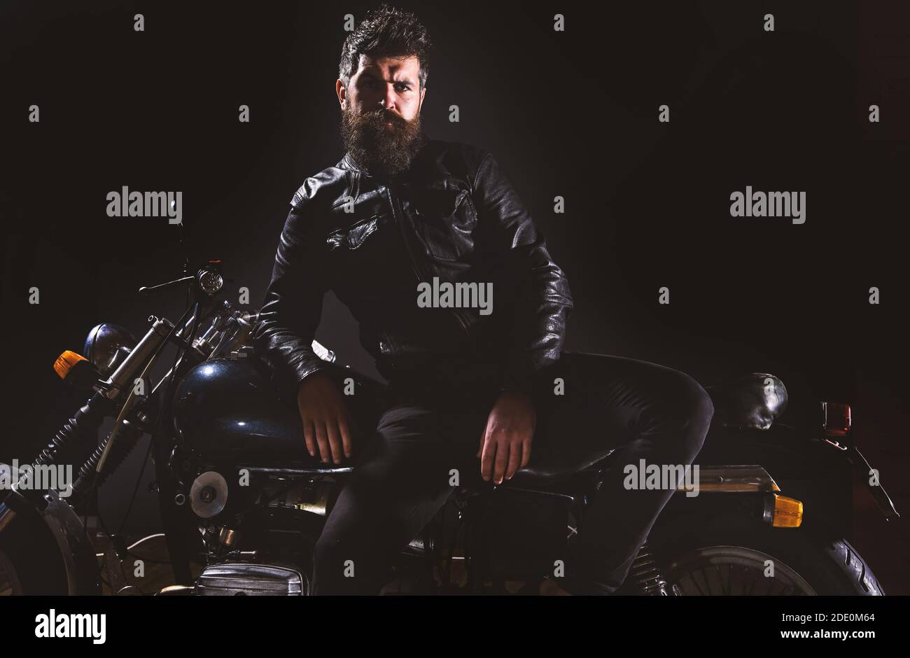 Macho, motard brutal dans un support de veste en cuir près de la moto la  nuit, espace de copie. Concept de culture du motard. Homme avec barbe,  motard dans la veste en