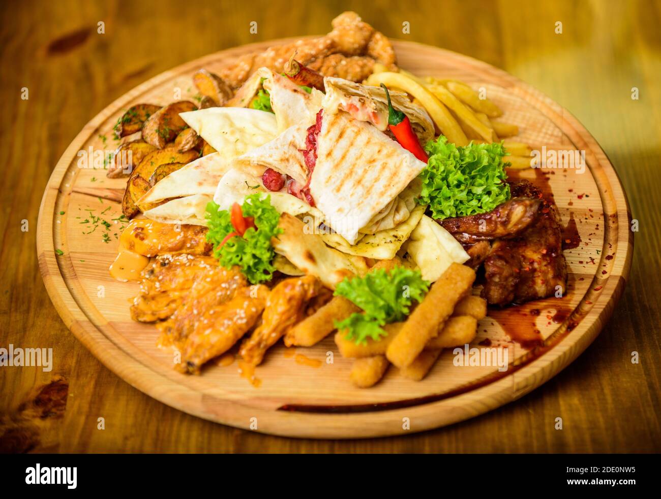 De délicieux en-cas savoureux. Snack pour la bière. Les repas au restaurant. Planche de bois avec beaucoup de frites et bâtonnets de poisson viande burrito steak servi avec une salade. Calories élevé pour le groupe d'amis. Menu snack-bar. Banque D'Images