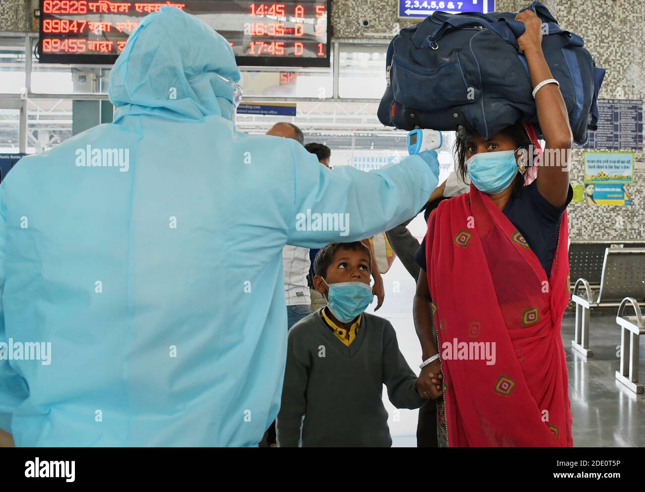 Mumbai, Inde. 27 novembre 2020. Un agent de santé vêtu d'un vêtement de protection vérifie la température corporelle d'une femme à la gare ferroviaire du Terminus de Bandra.les passagers voyageant du Rajasthan et du Gujarat ont été soumis à un contrôle de température à leur arrivée à la gare et, s'ils étaient suspects, ont été soumis à un test d'écouvillonnage dans les locaux de la station. Crédit : SOPA Images Limited/Alamy Live News Banque D'Images