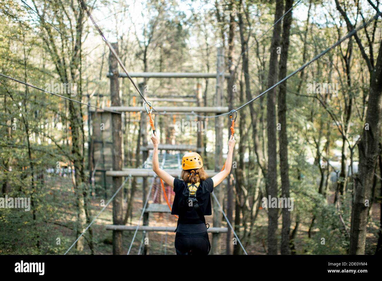 Jeune femme bien équipée ayant une activité de loisirs, des cordes d'escalade dans le parc avec des obstacles à l'extérieur Banque D'Images