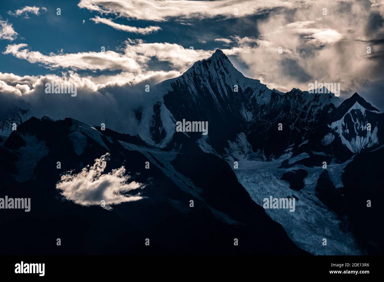 Nuage blanc vif en face du pic de Kawagarbo dans la chaîne de montagnes de l'Himalaya entre le Yunnan et le Tibet (Chine) au crépuscule sous un ciel orageux. Kawagarbo i Banque D'Images